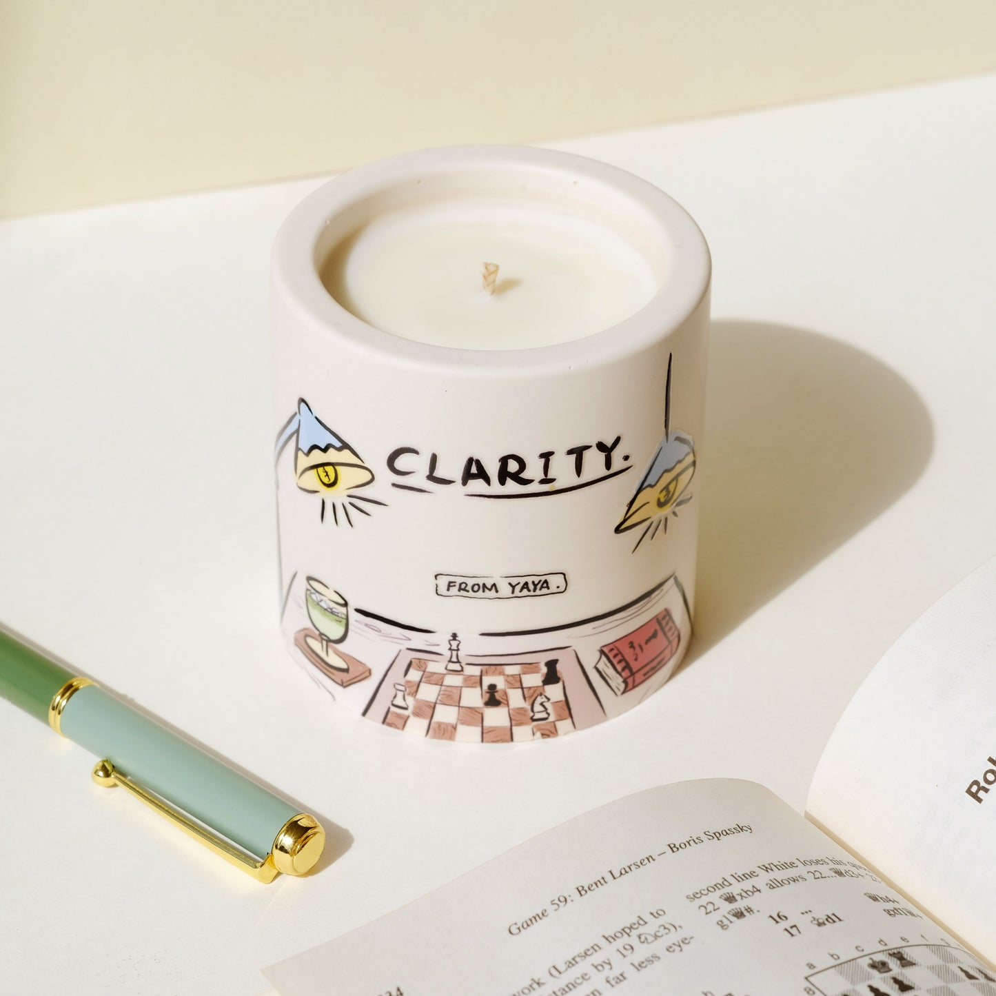 Clarity essential oil candle with illustration of chess and a book.
