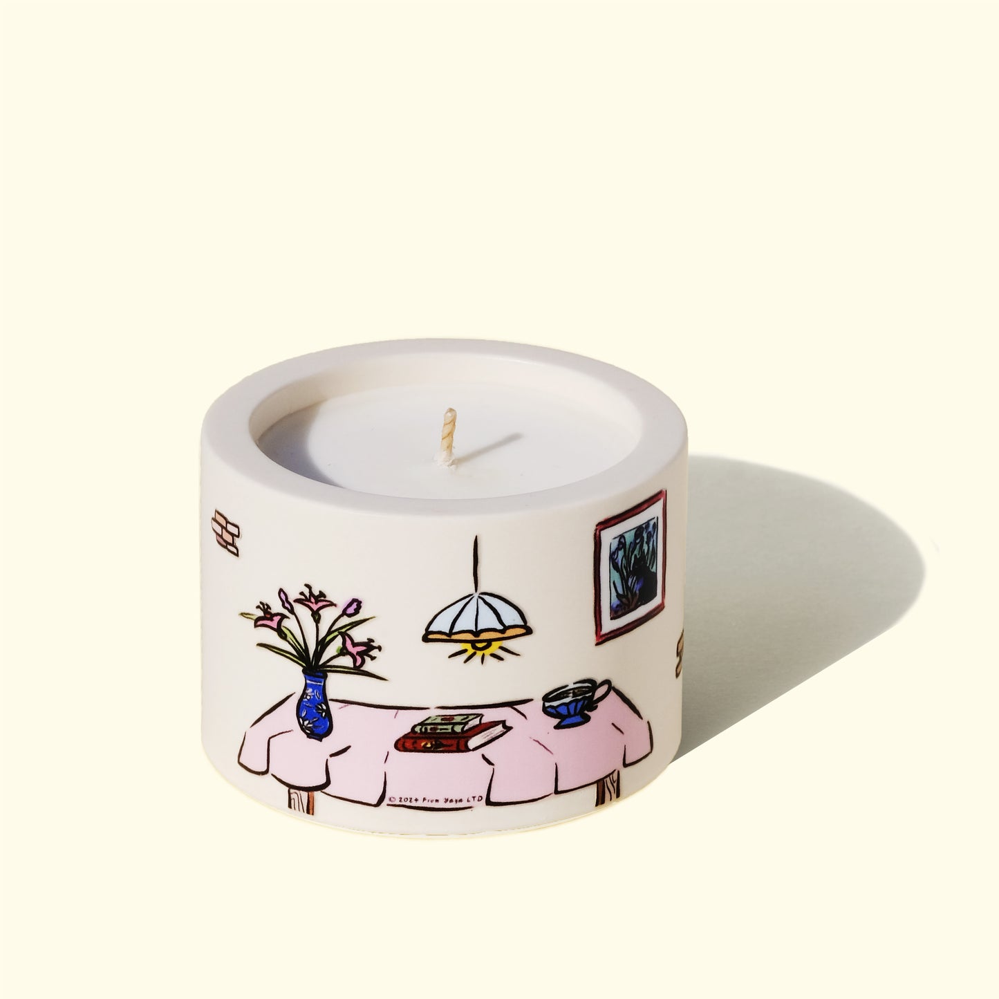 Backside of joyful essential oil candle. Illustratoin of a table with books, flowers and a cup of tea.
